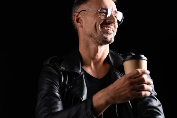 Foyer sélectif de sourire bel homme dans des lunettes de soleil tenant café pour aller isolé sur noir — Photo de stock