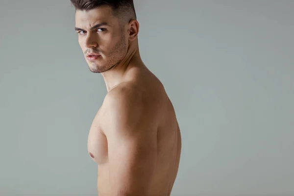Сексуальний м'язистий культурист з голим торсом дивиться на камеру ізольовано на сірому — стокове фото