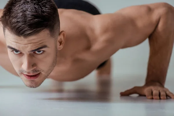 Sexy muscular bodybuilder with bare torso doing push ups — Stock Photo