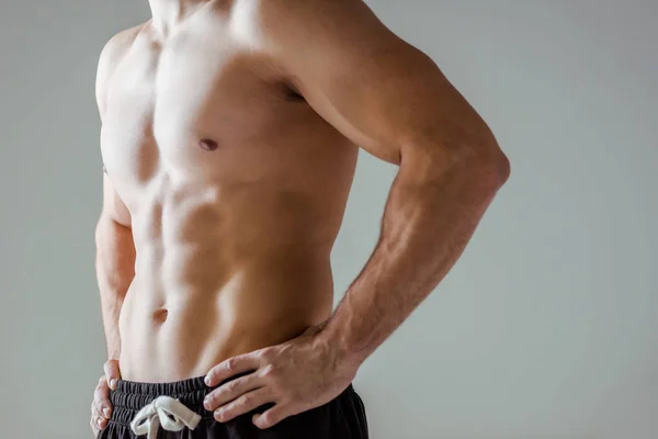 Vista recortada de culturista muscular sexy con torso desnudo posando con las manos en las caderas aisladas en gris - foto de stock