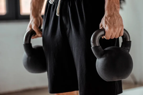 Partial view of bodybuilder holding kettlebells — Stock Photo