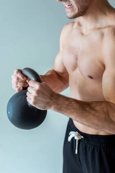 Visão parcial do fisiculturista muscular sexy com exercício de tronco nu com kettlebell isolado em cinza — Fotografia de Stock