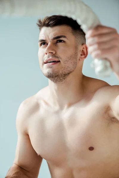 Сексуальный мускулистый культурист с голым туловищем тренирующийся с боевой веревкой изолированный на сером — стоковое фото