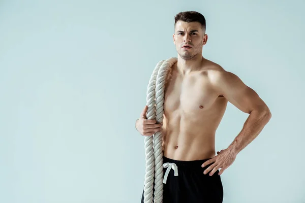 Sexy musculoso culturista con torso desnudo posando con cuerda de batalla aislado en gris - foto de stock