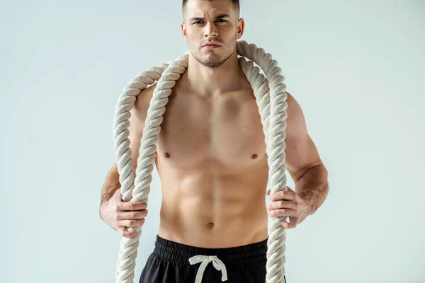 Fisiculturista muscular sexy com tronco nu posando com corda de batalha isolada no cinza — Fotografia de Stock