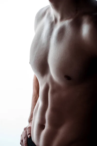 Vista parcial de sexy musculoso culturista con torso desnudo posando en sombra aislado en blanco - foto de stock