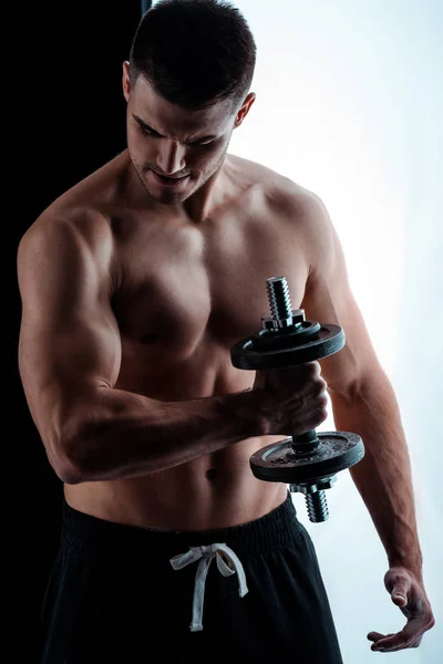 Sexy muscular bodybuilder with bare torso exercising with dumbbell — Stock Photo