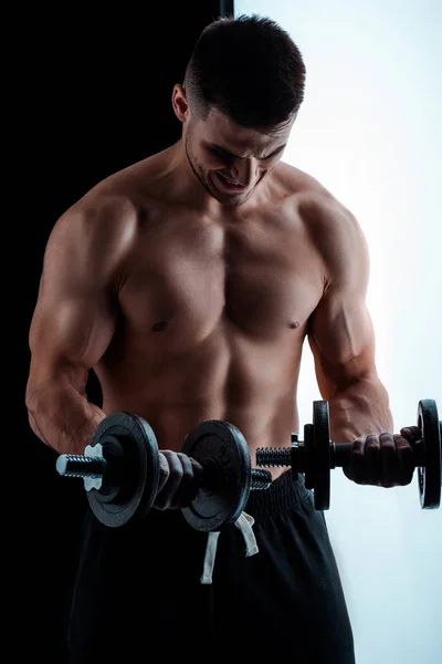 Sexy muscular bodybuilder with bare torso exercising with dumbbells — Stock Photo