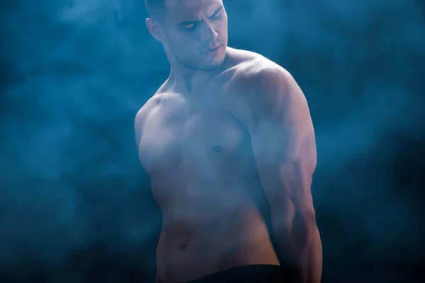 Сексуальный культурист с голым туловищем на черном фоне с дымом — стоковое фото