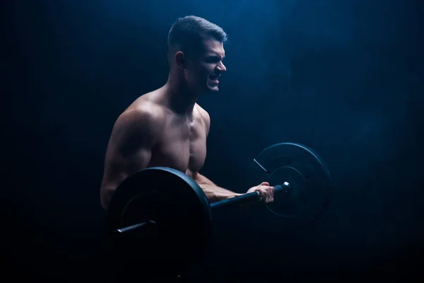 Teso sexy bodybuilder muscolare con torso nudo asportazione con bilanciere su sfondo nero — Foto stock
