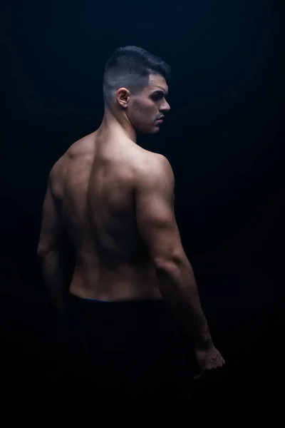 Back view of sexy muscular bodybuilder with bare torso posing isolated on black — Stock Photo