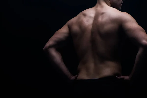 Partial view of sexy bodybuilder with muscular back posing isolated on black — Stock Photo