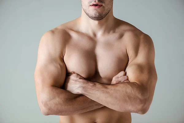 Vista recortada de culturista muscular sexy con torso desnudo posando con brazos cruzados aislados en gris - foto de stock