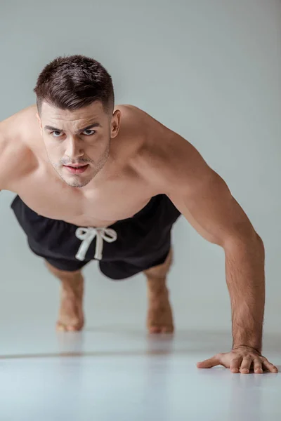 Sportif musclé sexy avec torse nu faisant push ups sur gris — Photo de stock