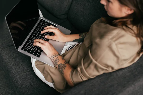 Vista aerea della donna che utilizza laptop con schermo vuoto sul divano, messa a fuoco selettiva — Foto stock