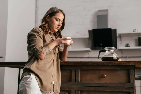 Красива молода жінка п'є каву на кухні — стокове фото