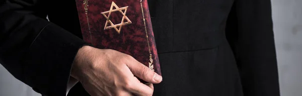 Panoramic shot of young jewish man holding tanakh — Stock Photo