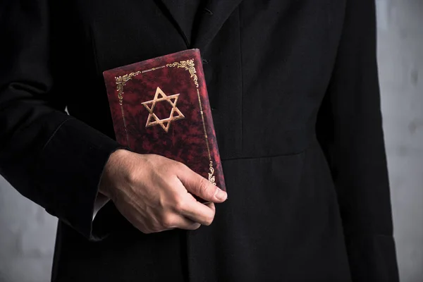 Cropped view of young jewish man holding tanakh — Stock Photo