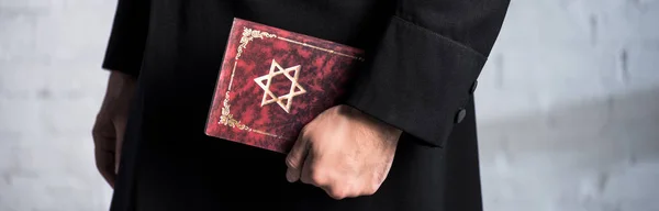 Panoramic shot of young jewish man holding tanakh — Stock Photo