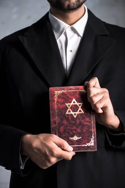 Cropped view of young jewish man holding tanakh — Stock Photo