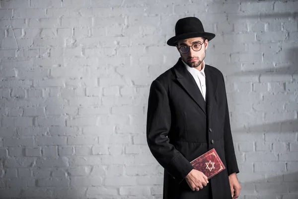 Handsome and sad jewish man in glasses holding tanakh — Stock Photo