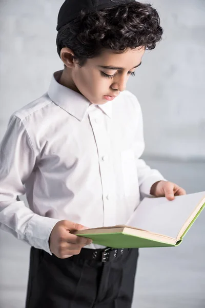 Cute jewish boy in white shirt reading book — Stock Photo