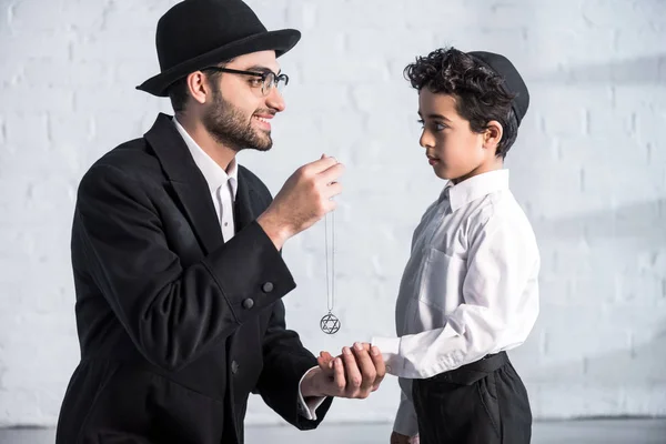 Side view of smiling jewish father giving star of david necklace to son — Stock Photo