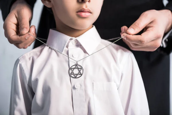 Cropped view of jewish father wearing star of david necklace on son — Stock Photo