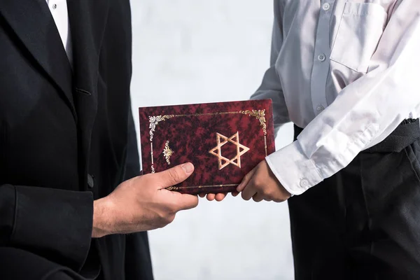 Corte vista de judeu pai e bonito filho segurando tanakh — Fotografia de Stock