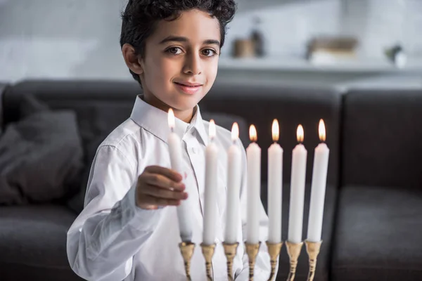 Niedlicher und lächelnder jüdischer Junge im Hemd mit Kerze — Stockfoto