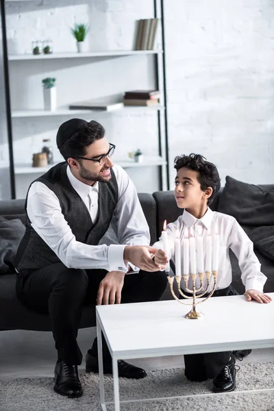 Sorrindo pai judeu e filho segurando vela no apartamento — Fotografia de Stock