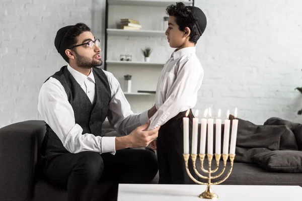 Padre judío y lindo hijo tomados de la mano en el apartamento - foto de stock