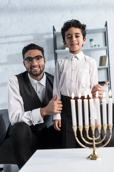 Lächelnder jüdischer Vater und Sohn blicken in Wohnung in die Kamera — Stockfoto