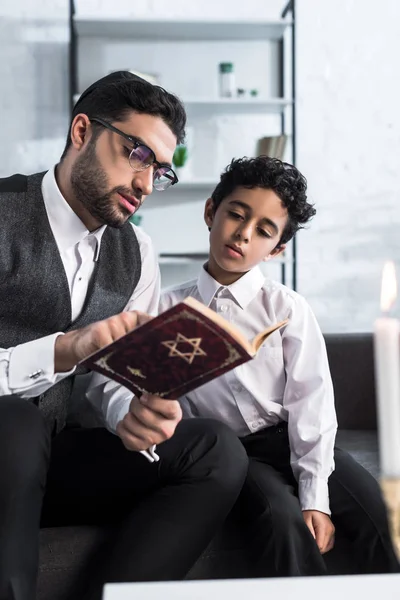 Bello ebreo padre e figlio lettura tanakh in appartamento — Foto stock