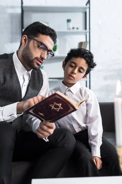 Handsome jewish father and son reading tanakh in apartment — Stock Photo