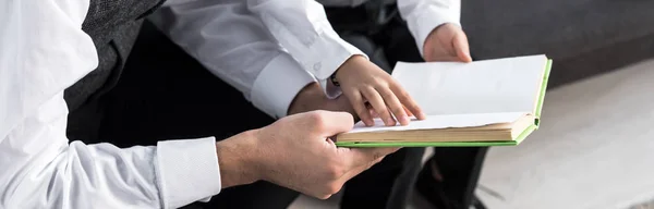 Панорамный снимок еврейского отца и сына, читающих книгу в квартире — стоковое фото