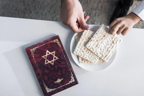 Cropped view of jewish father and son taking matza in apartment — Stock Photo