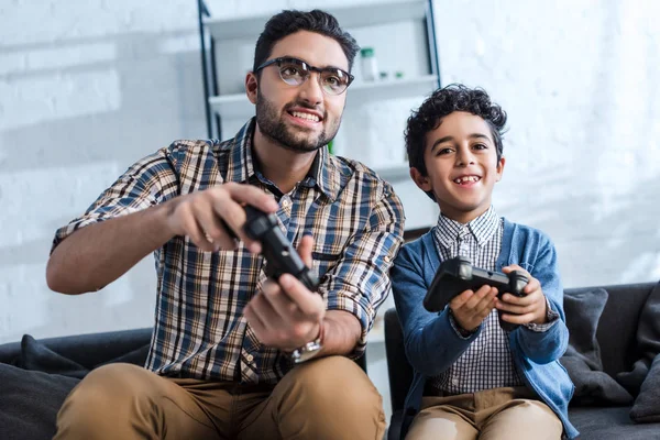 KYIV, UKRAINE - OCTOBER 15, 2019: smiling jewish father and son playing video game — Stock Photo