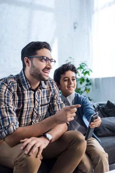 Smiling jewish father pointing with finger and watching tv with son — Stock Photo