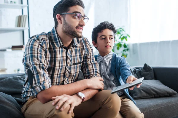 Souriant père juif et fils avec télécommande regarder la télévision — Photo de stock