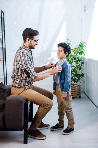 Vista laterale del padre ebreo sorridente che guarda il figlio in appartamento — Foto stock