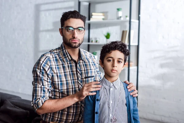 Еврейский отец обнимает сына и смотрит в камеру в квартире — стоковое фото