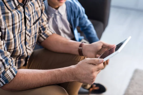 Vista recortada de padre e hijo judíos usando tableta digital en apartamento - foto de stock