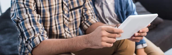 Panoramic shot of jewish father and son using digital tablet in apartment — Stock Photo
