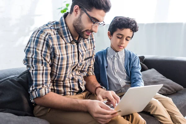 Jüdischer Vater und süßer Sohn benutzen Laptop in Wohnung — Stockfoto