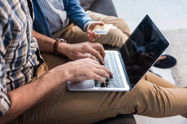 Vista ritagliata del padre ebreo utilizzando laptop e figlio in possesso di carta di credito in appartamento — Foto stock