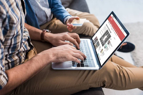 QUIIV, UCRÂNIA - OUTUBRO 15, 2019: visão recortada do pai judeu usando laptop com site bbc e filho segurando cartão de crédito — Fotografia de Stock