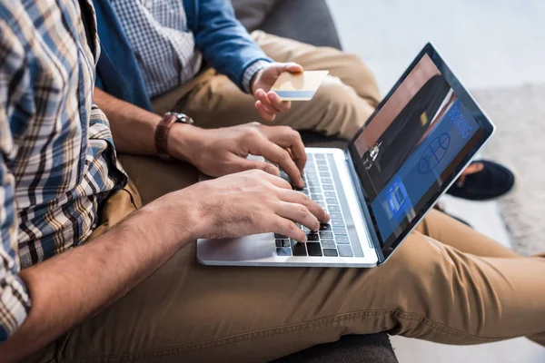 Ausgeschnittene Ansicht des jüdischen Vaters mit Laptop mit Buchungswebseite und Sohn mit Kreditkarte — Stockfoto