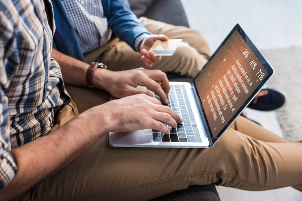 Visão cortada do pai judeu usando laptop com site e filho segurando cartão de crédito — Fotografia de Stock