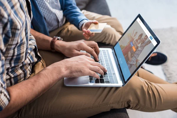 KYIV, UKRAINE - OCTOBER 15, 2019: cropped view of jewish father using laptop with couchsurfing website and son holding credit card — Stock Photo